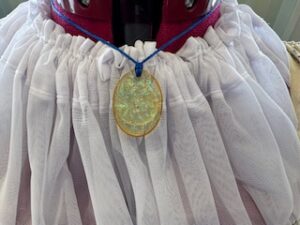closeup of necklace over a collar made from gathered white material. Necklace is a little sparkly.